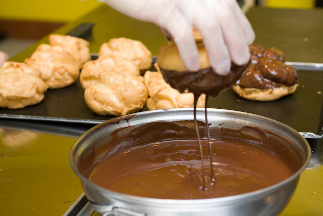 Pastry shells getting a dark chocolate coating.