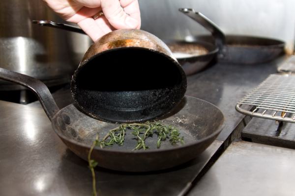 A thyme sprig in a pan with a metal funnel.  This is the beginning of the smoked salmon preparation.