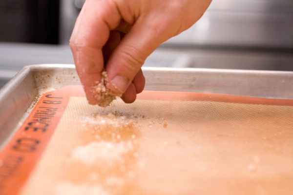 Sprinkling sugar on a silpat mat before going into the oven.