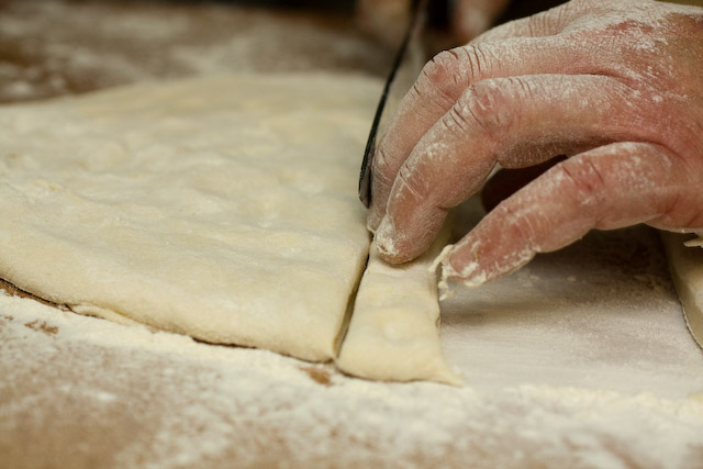 Using a sharp knife, Chef Perdue cuts a strip of pasta dough.