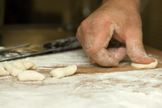 Each small piece of pasta dough then gets a quick press and roll across the board with Chef\'s thumb.