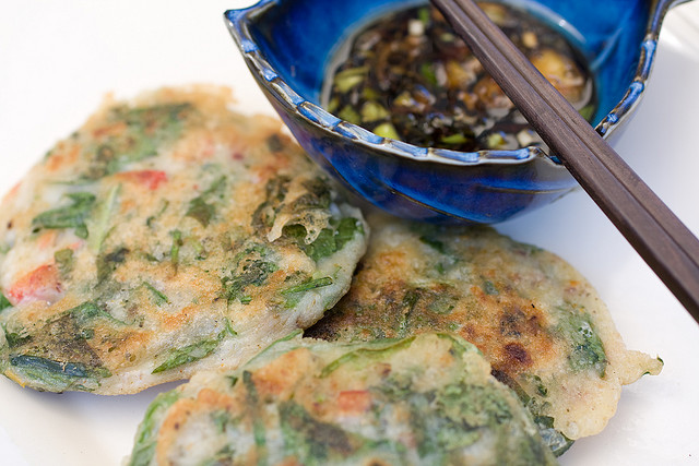 Vegetable pancakes with a side of soy sauce with chopped scallions.