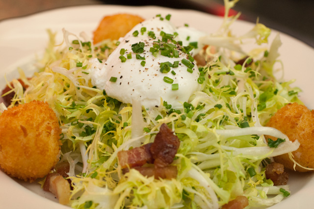 FrisÃ©e lardons with poached egg, ham and cheese croquettes.