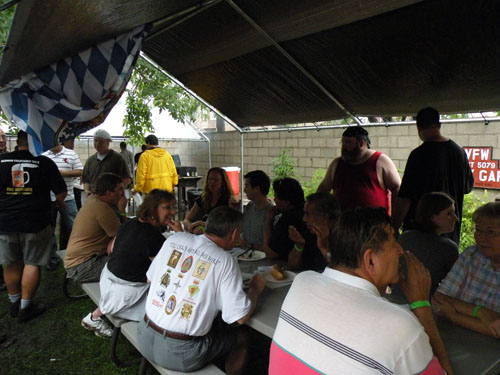 Attendees wait out the intermittent showers underneath a tent.