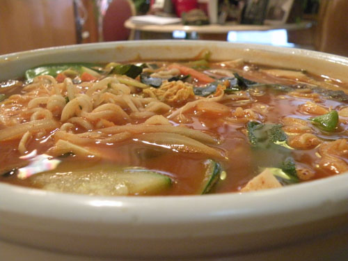 Amitabul\'s famous \"Cure-all\" soup.  Choi promises that this spicy broth teeming with mushrooms, tofu, noodles, seaweed and vegetables can help rid the eater of cold, flu and hangovers.  It is tasty.