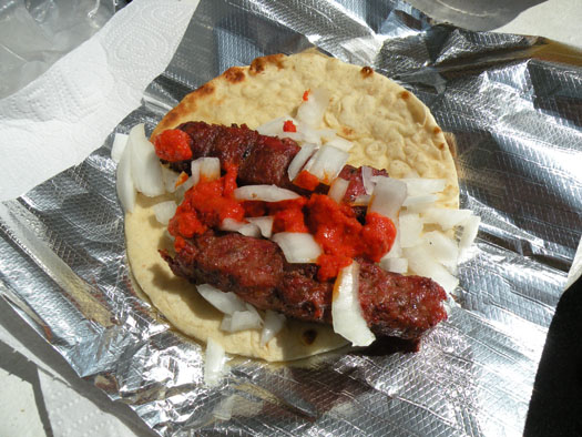 Here is ÄevapÄiÄi served medium on grilled pita with raw onions. The sauce is a roast red pepper and eggplant relish seasoned with cayenne that\'s very easy to make at home.