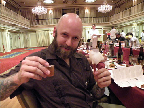 Three Floyds \"Minister of Propoganda\" Lincoln Anderson holds up Sam Burman\'s bacon-infused Manhattan and bacon cotton candy on a crispy bacon stick.