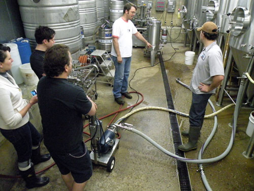 Sheahan (\<em\>right\<\/em\>) sanitizes a conditioning tank while Kahan, McAvena and Haggerty watch.