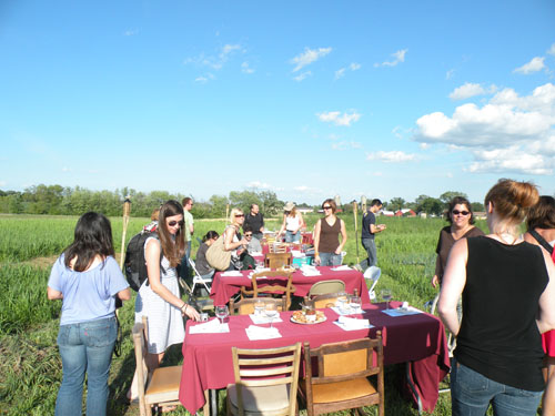 Attendees sit down to dinner in the middle of the field.
