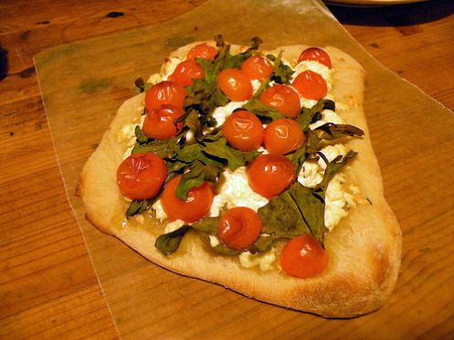 A flatbread made with fresh cherry tomatoes, minestra nera and chevre de Provence