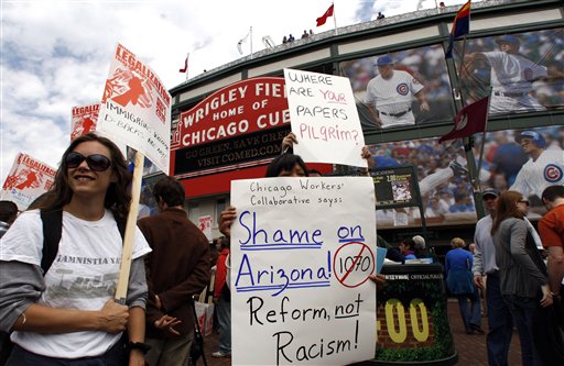 Kyla Klein, left, and Claudia Galeno hold signs as they protest at Wrigley Field.