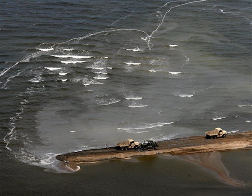 Military vehicles dump material as they build a berm across an opening in the beach just west of Grand Isle, Louisiana on Monday