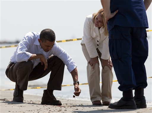 Obama inspecting a \"tar ball\" as LaFourche Parish president Charlotte Randolph, center, and U.S. Coast Guard Admiral Thad Allen, National Incident Commander for the BP Deepwater Horizon oil spill, look on during a tour of areas impacted by the Gulf Coast oil spill, Friday, May 28, 2010 in Port Fourchon, La.