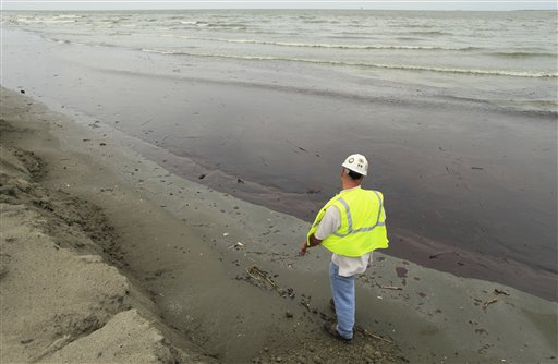 A worker walks along a beach drenched by oil at East Grand Terre Island, LA