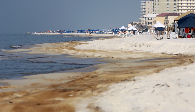 Oil cleanup crews work on an oil-stained stretch of sand in Orange Beach, Alabama.\r\n