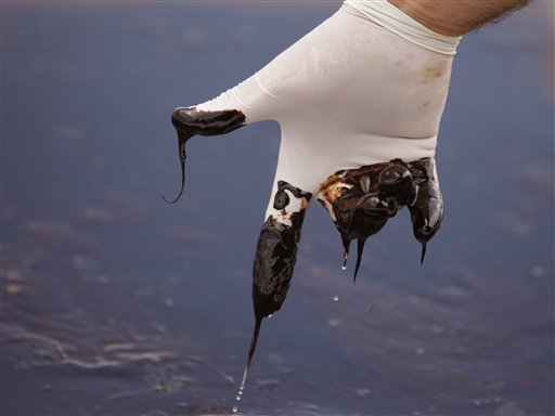 A member of Louisiana Gov. Bobby Jindal\'s staff stirs thick oil on the water\'s surface in the Northern regions of Barataria Bay in Plaquemines Parish, La., Tuesday, June 15, 2010.