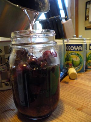 Filling a mason jar with the cherries and the syrup, which has had cognac added.