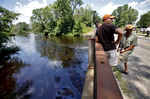 John Corcoran, center, and Cam Meyers, right, watch from the 15 Mile Road bridge as oil flows in the Kalamazoo River