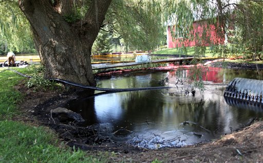 Oil flows into the Kalamazoo River as workers try to skim it off the surface in Marshall, Mich.