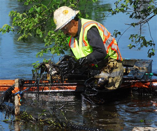 A worker lifts oil-covered debris from the Kalamazoo River in Battle Creek, Mich.