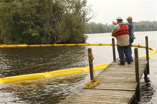 Frank Roberts, left, and Trever Miller, contract workers for Enbridge, Inc., Calgary, Canada, discuss the operation of placing booms across the Kalamazoo River.