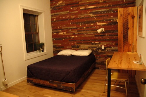 The bed frame and wall from this budget room was made with wood taken from the original floor of the space, formerly residential apartments