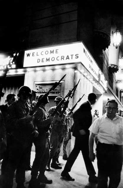 Mocking itself, this picture at the Hilton during the 1968 Dem Convention welcomed the delegates- but those National Guard riflemen called out by Mayor Daley, kept them from getting to their rooms. Paradoxes invariably make good pictures.