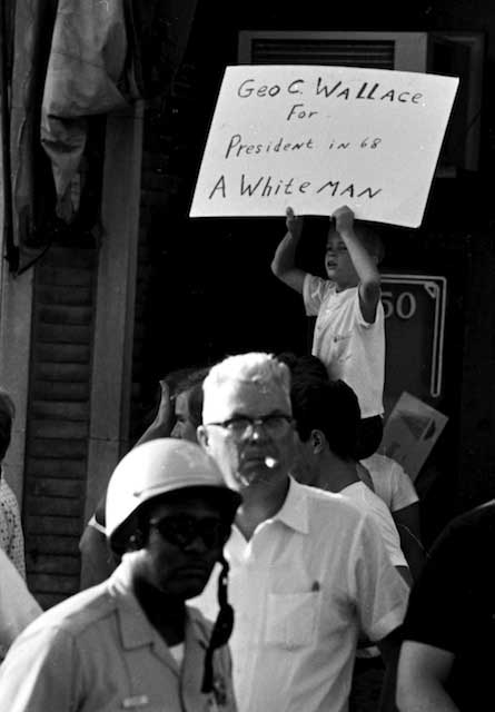 How might the black officer feel looking up at this 1968 homemade sign touting racist George Wallace for President? Main qualification: his skin color.