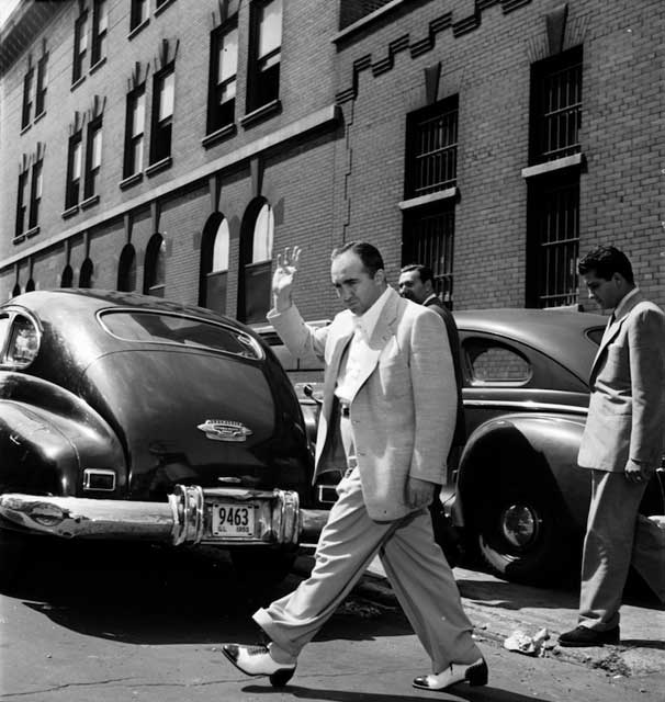 Another, but unofficial Jewish Mafia member, Mickey Cohen, and his strongarm man Johnny Stompanato leave Maxwell Street police station after they were warned to leave town by sundown. \"The Stomp\" would be murdered a few weeks later by his girlfriend Lana Turner\'s 14-year-old daughter, wielding a kitchen knife when he allegedly tried to molest her. Word on Hollywood Boulevard was that Lana killed Stompanato, but had the presence of mind to call the great lawyer Jerry \"Get Me\" Giesler at 3 a.m. to work out a murder s\cript more amenable to the police. Like maybe Lana killed him for pimping on the side or siphoning money from her account- and somehow was persuaded that a jury would regard the sniffling of a 14-year-old potential actress would be more believable than the impassioned sniffling of a veteran blonde leading lady known for portraying tragic bitches with lousy boyfriends.