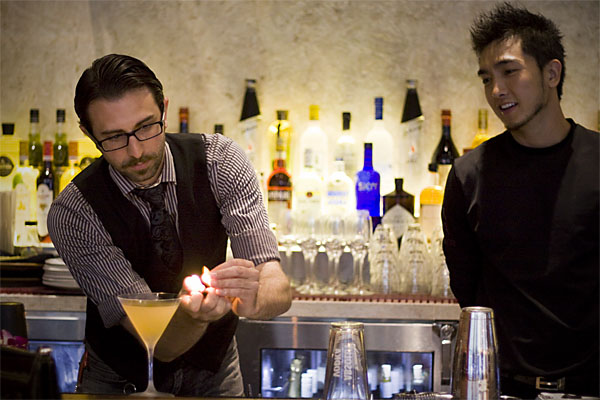 Dante LoPresti (left) ignites lemon oil over a freshly made \"THE ONE,\" his contribution to Roka Akor\'s cocktail menu.
