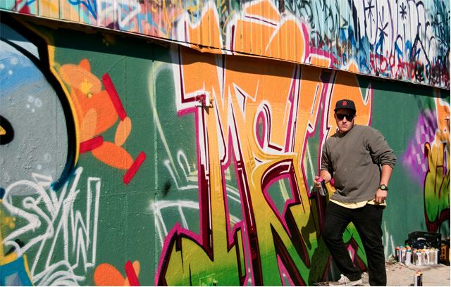 One of the emerging artists tags a colorful piece on the back wall. (Annie Grossinger, for Chicagoist)