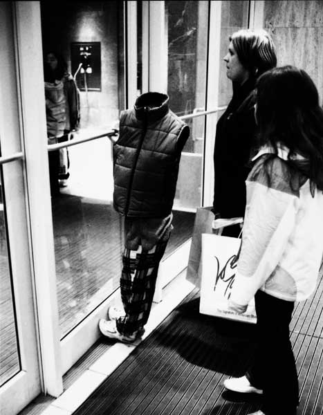 My wife, Florence, walking behind me through the exit door, heard the shutter of my Leica click. (I was shooting from the hip with a wide-angle lens as I often do.) \"What on earth did you see?\" she asked.  \"A Lord & Taylor shopper,\" I said, \"with a restless, headless, armless son. Why do you ask?\" [Image Credit: Art Shay]