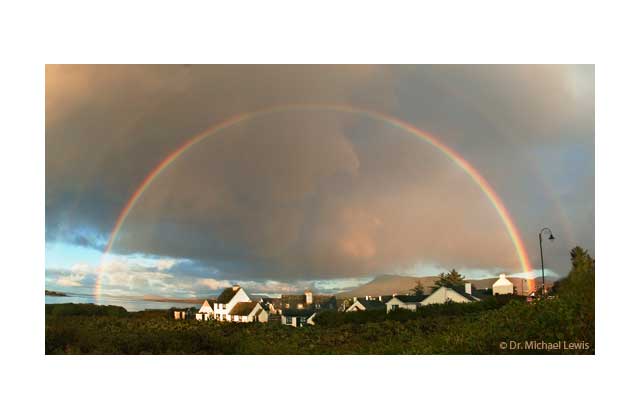 The nondes\cript tiny Irish village of Achill Island, located off the coast of County Mayo, has its beauty enhanced by the Lewis Nikon and a natural  rainbow. Like all true nature photographers, Lewis eschews Photoshop which is capable of even  adding angels, or God Himself, to the rainbow coalition. If Lewis found the pot of gold at the end of the rainbow, don\'t you know, begorra, for sure he\'d have donated it to the Cataract Project.\r\n