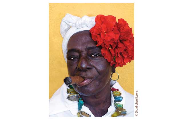 This tough old Cuban grandma unflinchingly poses for the Lewis telephoto smoking the island\'s most famous export. The compositional balance of this pictureâflowers,necklace, cigar, faint mocking smileâdelights my critical eye. I have seen much less artful museum murals and giant  $100,000 self portraits of a wildly successful lady fotog who\'s devoted her professional life to pictures of herself in various cute get-ups. Like this one. \r\n