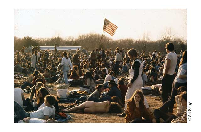 At a rock concert near Madison in the 1970s, under a big flag with an elm tree branch holding it proudly aloft waved over fields of spaced out celebrants.\r\n