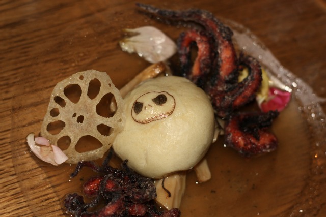 \"Jack\'s Lament\" - Baby octopus that has been poached in an aromatic oil.  This is served in a\r\ndashi broth with roasted trumpet mushrooms and a steamed bun stuffed with mushroom duxelle\r\nbrandishing Jack Skellingtonâs face on it. There is also a crispy lotus root chip and flower petals.